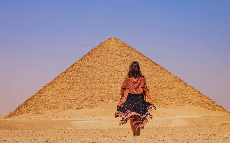 a woman traveler stands amazed by the splendor of the red pyramid
