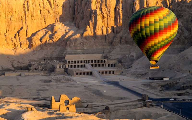 hot air balloon flying over the temple of hatshepsut in