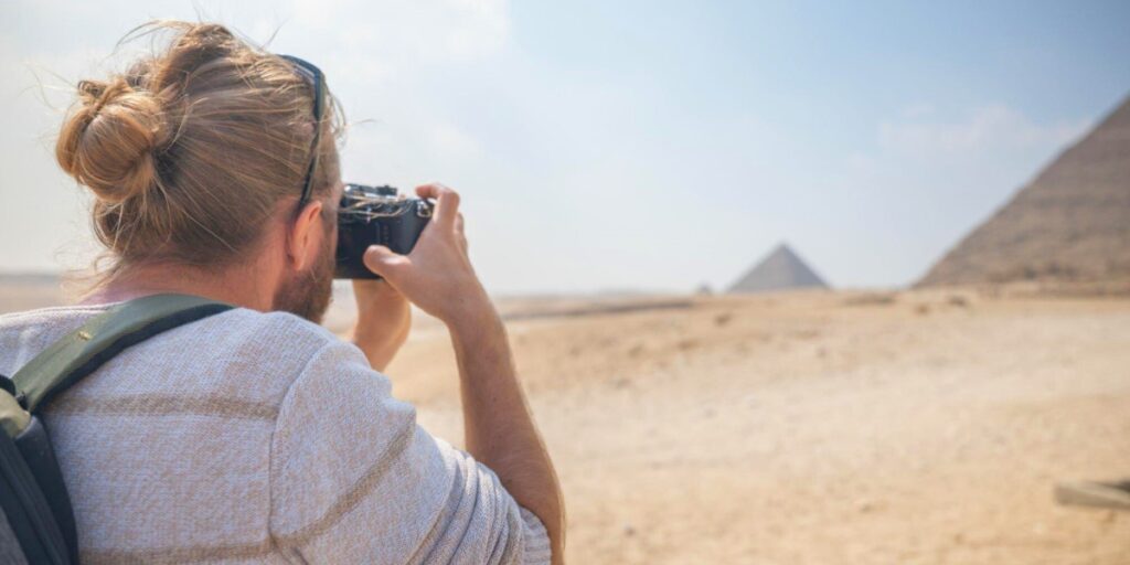 male tourist takes photos of the pyramids in egypt